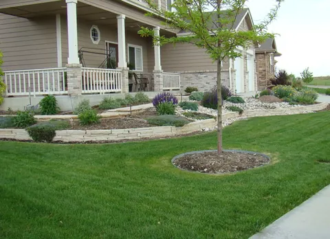Low flagstone edging along a mulch bed in front of a porch and green lawn.