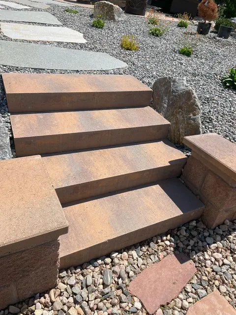 Tan paver steps climb a gravel slope with flagstone stepping pads in Fort Collins.