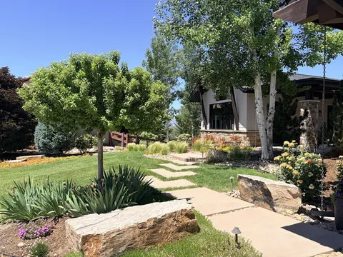 Flagstone path through a front lawn past large boulders and ornamental grasses in Fort Collins.