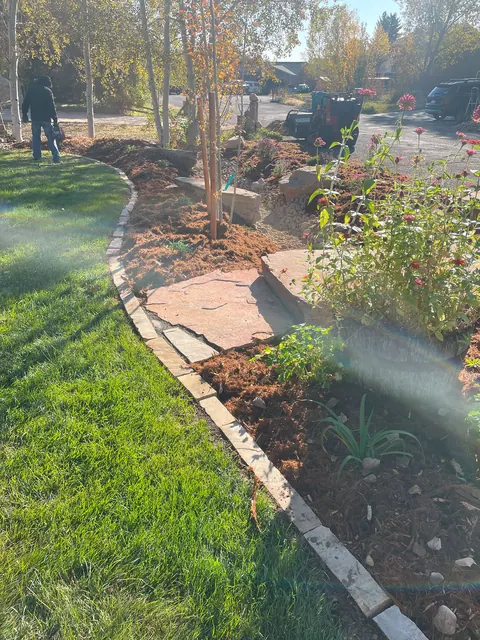 Stone edging separates a curving lawn from mulch, flagstone and perennials in a Loveland landscape.