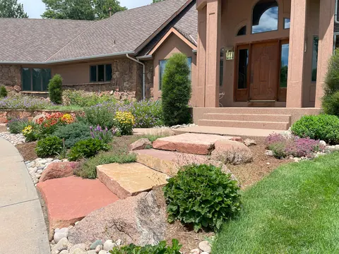 Red flagstone steps and boulders lead through a perennial garden to a Fort Collins front door.