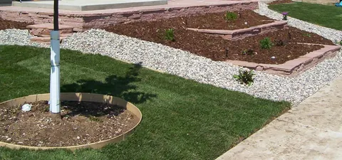 Flagstone edging around a raised mulch bed beside a lawn with a gravel border.