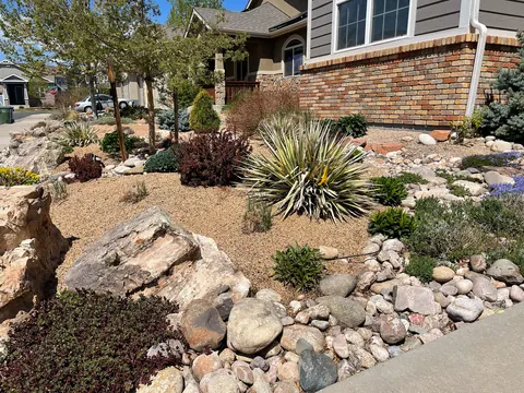 Yucca, red shrubs and sandstone boulders in a gravel and river rock xeriscape bed in Loveland.